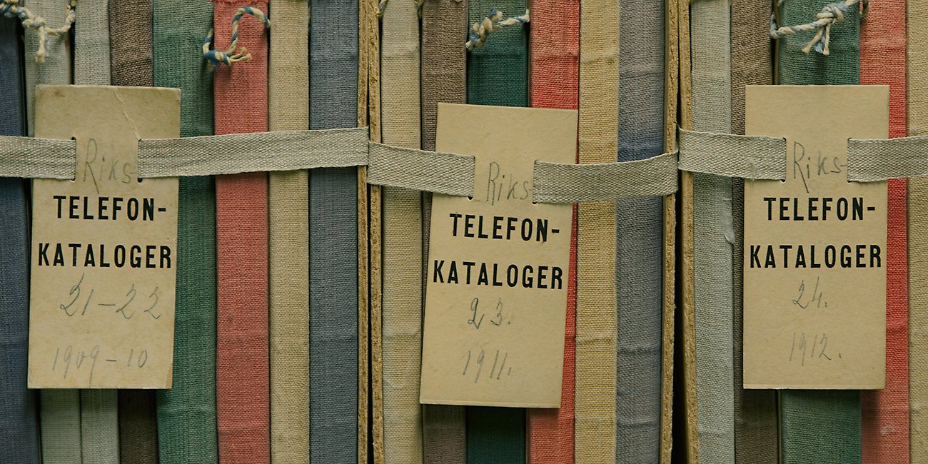 Färgglada bokryggar med etiketter där det står telefonkatalog och åren 1909 till 1912. 