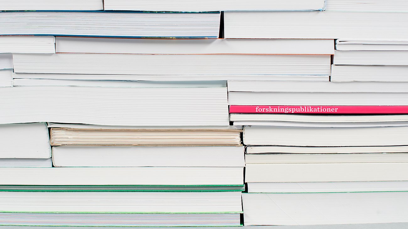 Böcker staplade på varandra. På en av bokryggarna står Forskningspublikationer.