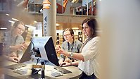 Två bibliotekarier vid en dator – den ena pekar på skärmen.