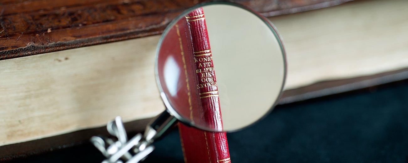 Liten bok bakom förstoringsglas. Beskuren.