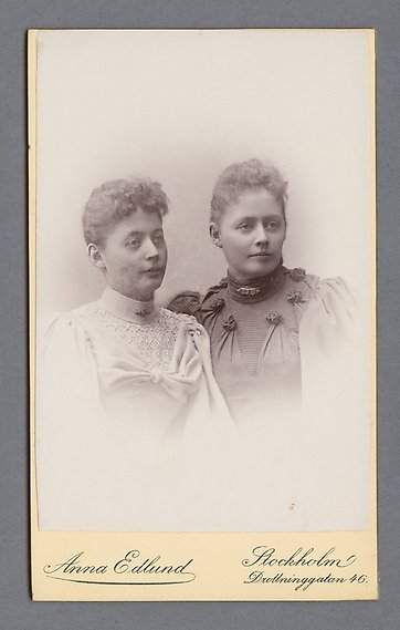 Svartvitt fotografi av två kvinnor som tittar ut ur bild.