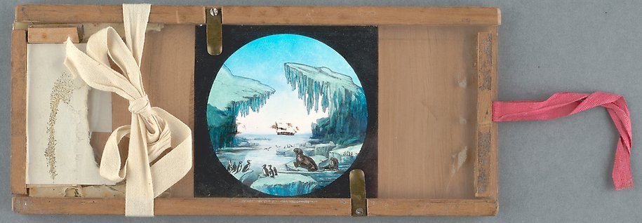 Målning fäst i träram, på fotot syns också röda och vita tygband samt fästen på träramen. På målningen syns skeppet till havs, i förgrunden står sjöfåglar, pingviner och valrossar och verkar betrakta skeppet i fjärran.