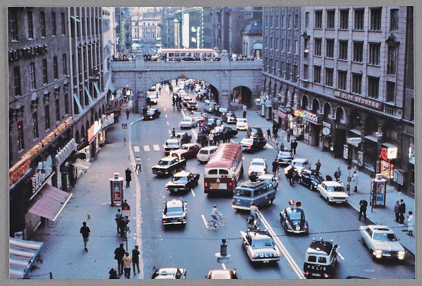 Ett färgfotografi med vy över Kungsgatan där bilar och bussar som nu börjat byta sida av trafiken. Polisbilar. Gångtrafikanter tittar på.