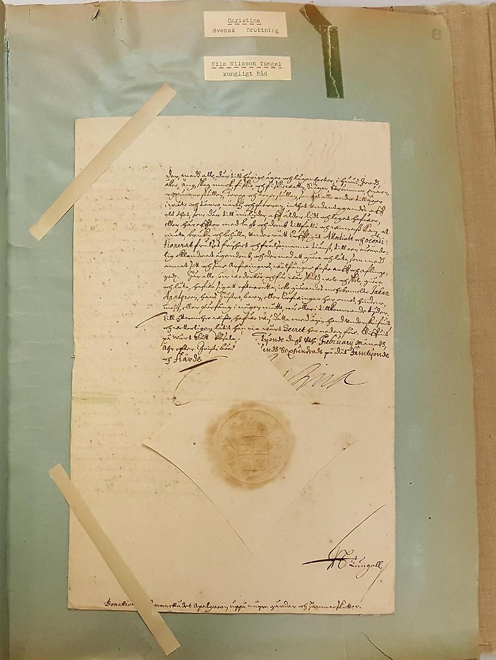 Handskriven text med drottning Kristinas autograf på ett slitet och tejpskadat blått ark.