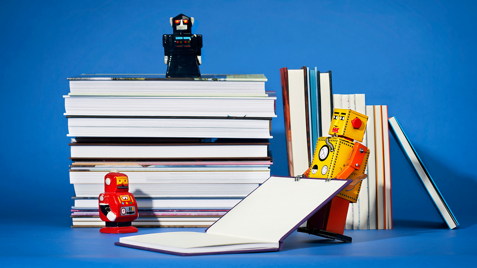 Staplade böcker med små robotar som står på böckerna och en robot som lyfter en bok.