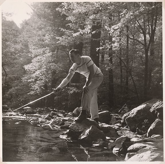 En man står på en sten med fiskespö